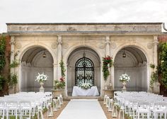 an outdoor ceremony with white chairs and flowers