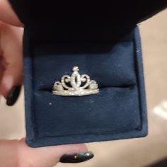 a woman's hand holding a ring with a tiara on top of it