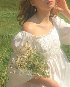 a woman in a white dress is standing in the grass with her hand on her head