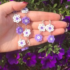 a hand holding purple and white flowers in it's left hand, next to purple flowers