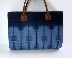 This unique and beautiful designed blue handbag is perfect for casual or formal occasions.This blue handbag...•is hand dyed in natural indigo;•has Japanese shibori pattern, Katano shibori;•has a one-of-a-kind pattern;•has different shades of blue on each side;•is sewn by me;•has an in-lining pocket;•has a hook for keys;•includes multiple layers of interfacing for sturdiness and softness; and•has real leather shoulder straps.Material: cotton (front & back) / linen (sides and inside) / real leathe Blue Square Satchel With Handles, Blue Rectangular Satchel With Handles, Blue Rectangular Shoulder Bag With Rolled Handles, Blue Shoulder Bag With Rolled Handles For Daily Use, Blue Handheld Shoulder Bag With Leather Handles, Blue Shoulder Bag With Double Handles, Everyday Indigo Rectangular Bag, Rectangular Indigo Everyday Bag, Modern Blue Bags With Rolled Handles