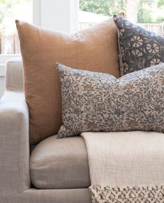 a couch with pillows on top of it in front of a window and some windowsills