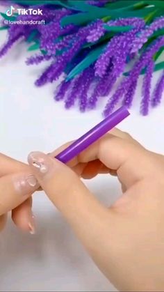 a woman is holding a purple pen in her left hand while another person holds it with their right hand