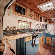 the interior of a small camper with blue cabinets and wood flooring, including a kitchen