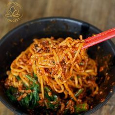 a black bowl filled with noodles and vegetables