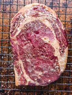 a piece of meat sitting on top of a wire rack next to some seasoning