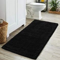 a bathroom with a black rug on the floor and a white toilet in the background