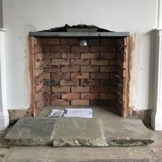 a brick fireplace is being built in the middle of a room with white walls and pillars