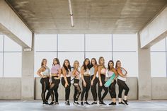 a group of young women standing next to each other in front of a wall with windows