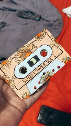 a hand holding a wooden toy with an old fashioned cassette on it's side