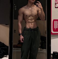 a shirtless man taking a selfie in the mirror