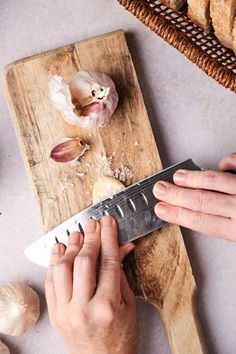 a person is cutting up some food on a wooden board with a knife and garlic