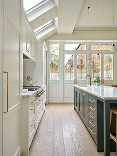 a kitchen with an island and skylight in it's center window, along with two stools on either side of the counter