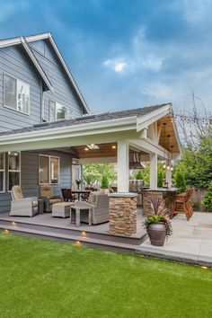 an outdoor living area with patio furniture and grass in front of a blue house on a sunny day