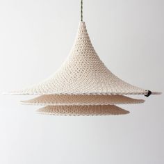 a crocheted light fixture hanging from a white ceiling with green stems sticking out of it