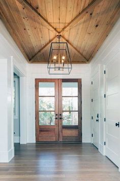 an empty room with two doors and a chandelier hanging from it's ceiling