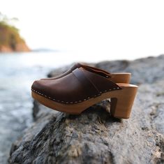 Wooden Closed Toe Clogs With Stacked Heel, Wooden Clogs With Stacked Heel And Closed Toe, Rubber Sole Slingback Clogs, Brown Clogs With Rubber Sole And Block Heel, Rustic Brown Slip-on Clogs, Rustic Brown Closed Toe Mules, Brown Slingback Clogs With Wooden Heel, Wood Slip-on Mules, Rustic Slip-on Clogs With Wooden Heel