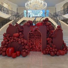 a large display of red fruit and vegetables in front of a chandelier at the bottom of stairs