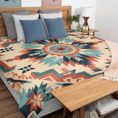 a bed with a colorful comforter on top of it next to a night stand