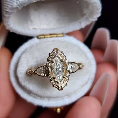 someone is holding an old diamond ring in their hand and it's inside the box