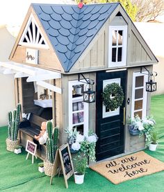 a doll house with potted cacti in front of it