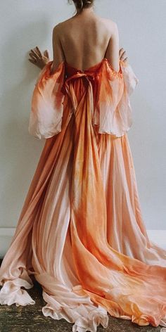 a woman in an orange and pink dress is standing back to back with her arms outstretched