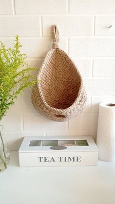 there is a basket hanging on the wall next to a vase with flowers in it