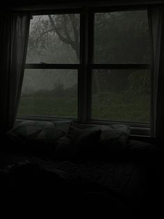 a bed sitting in front of a large window covered in foggy weather and trees