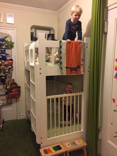 a young boy standing on top of a white bunk bed next to a green curtain