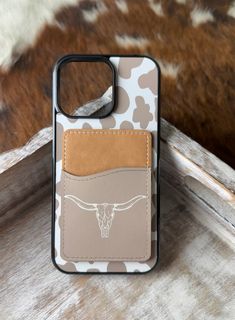 a cell phone case with a cow skull on the front and tan leather pocket for it