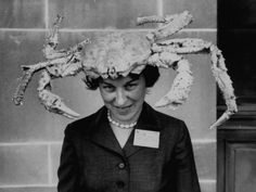 a woman wearing a crab hat in front of a wall with writing on the side