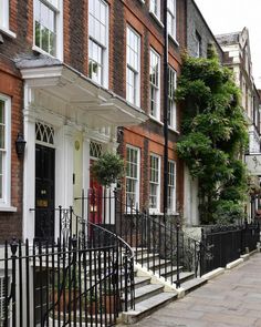 a row of red brick buildings with white windows and black wrought iron railings on the sidewalk