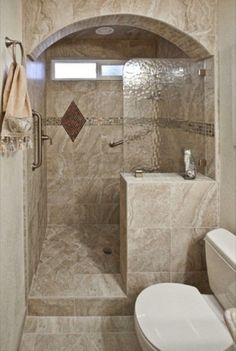 a walk in shower sitting next to a toilet and a sink with a window above it