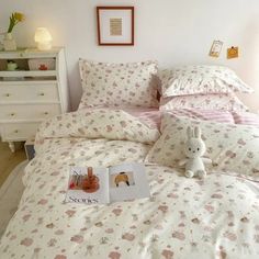 a bed with pink and white sheets, pillows and a stuffed animal