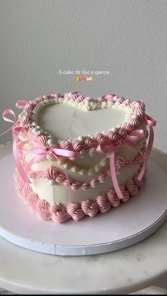 a heart shaped cake with pink ribbon on top