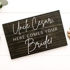 a wooden sign that says, under oscar here comes your bride on it next to some flowers