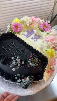 a birthday cake with flowers on it is being held by someone