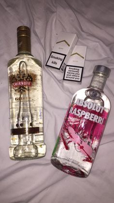 two bottles of alcohol sitting on top of a bed