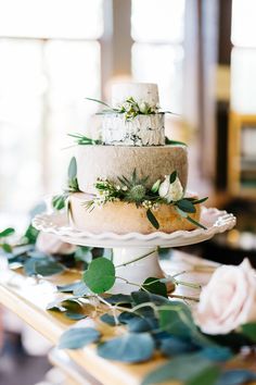 a three tiered cake with greenery on top