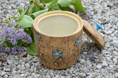 a wooden cup sitting on top of gravel next to flowers