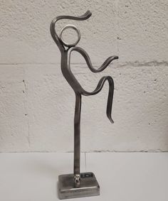 a metal sculpture is standing on a white surface