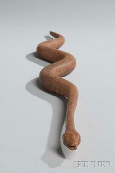 a wooden snake is laying on the floor with it's tail curled around its neck