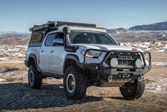 a truck parked on top of a dry grass covered field with mountains in the background