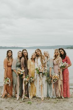 a group of women standing next to each other on a beach with flowers in their hair