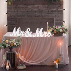 a table with flowers and candles on it is set up in front of a sign that says mr & mrs