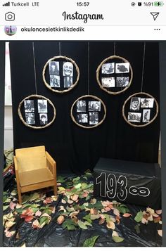 a chair and some pictures hanging on a black wall with leaves in front of it