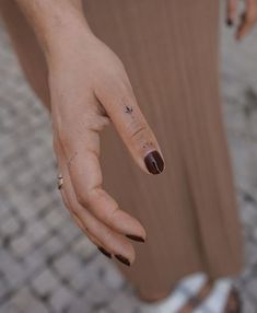 a woman's hand with a small tattoo on her left thumb and ring finger