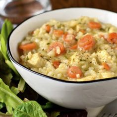 a white bowl filled with food next to lettuce and carrots