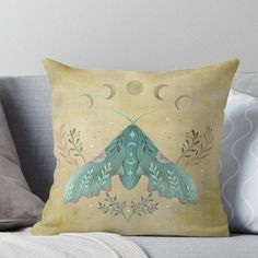 a blue moth sitting on top of a couch next to the moon and plants throw pillow