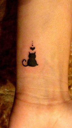 a small black cat tattoo on the wrist